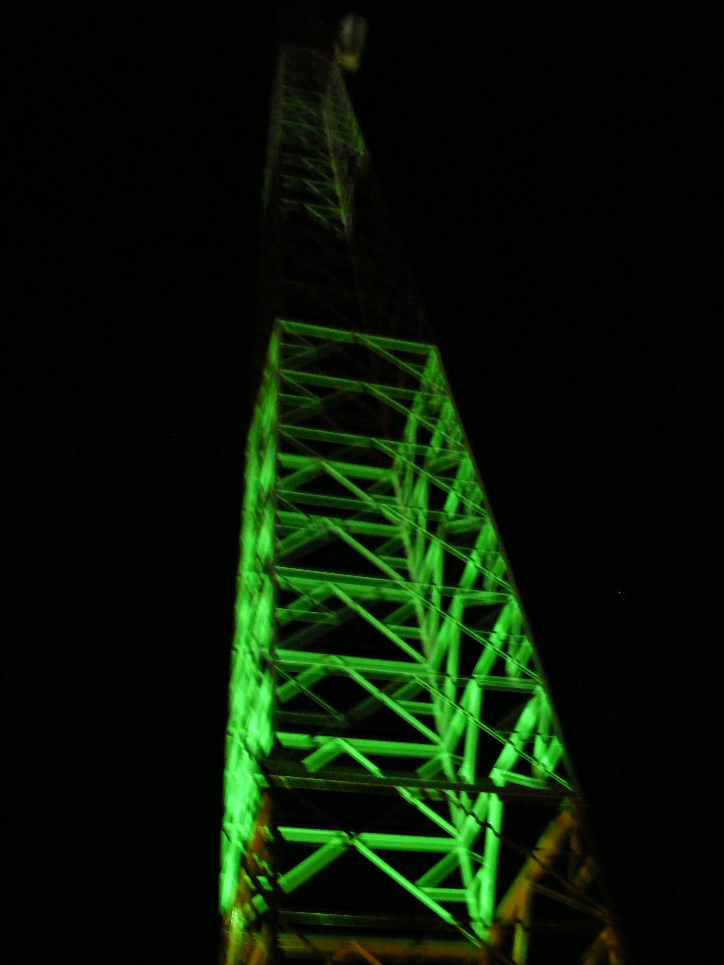 Foto da torre a noite com holofotes verdes apontados para cima, não ficou como eu esperava, mas mesmo assim, ficou bonita. Falta agora o strobo no topo que ainda vou colocar